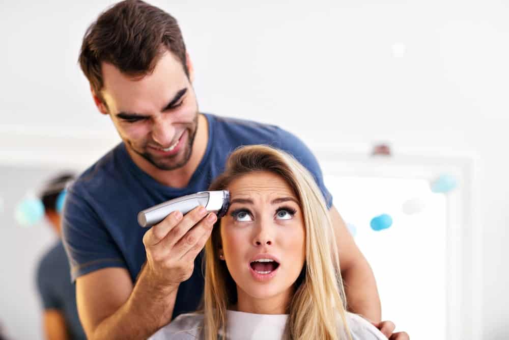 A woman at a hair salon about to have her head shaved.