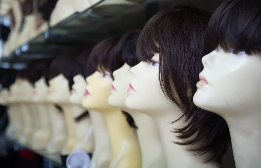 This is a close look at a row of various wigs on display at a store.