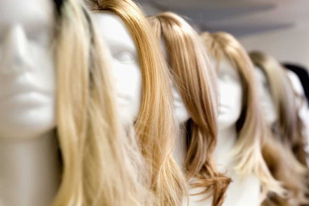 A close look at a row of various wigs on display at a store.