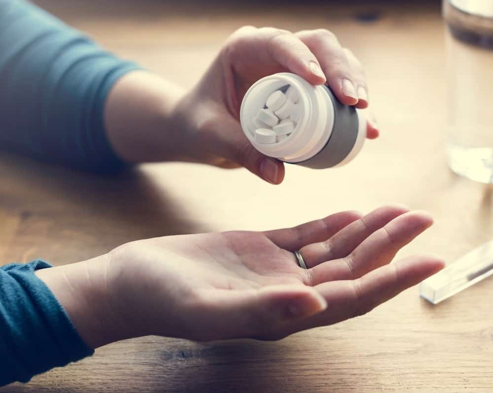 A close look at a man taking oral vitamin supplements.